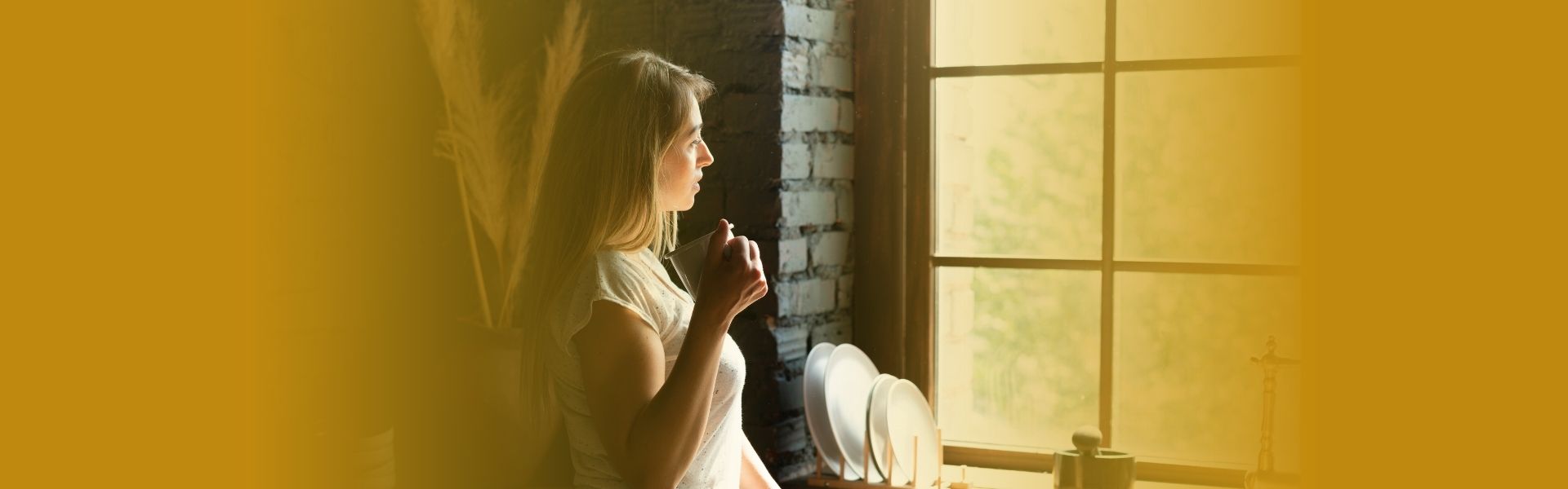Mulher sentada em ambiente acolhedor, com expressão reflexiva e tranquila, luz natural entrando pela janela, representando autocuidado emocional e processo terapêutico humanizado.