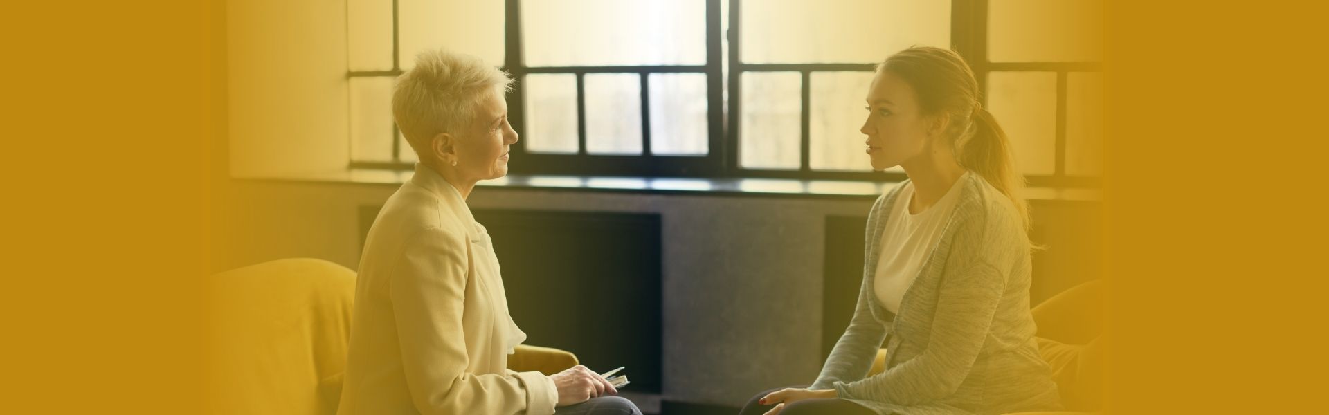 Pessoa sentada em consultório acolhedor, conversando com psicóloga, ambiente claro e tranquilo, transmitindo continuidade do cuidado emocional e confiança no processo terapêutico.